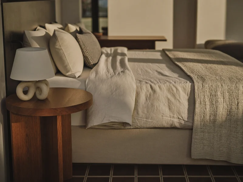Ruhiges Schlafzimmer mit Leinenbettwäsche, Holznachttisch und Keramiklampe